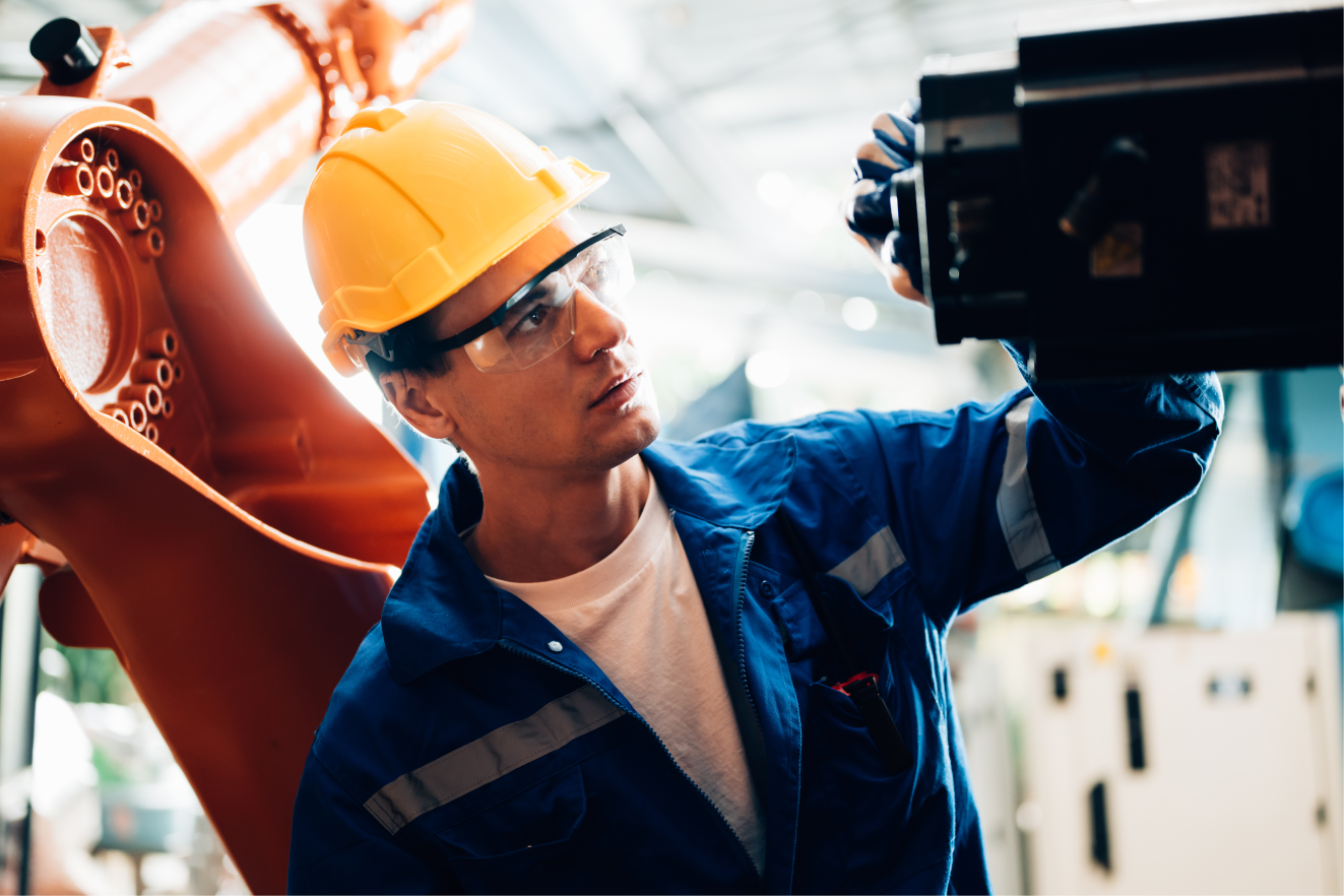 Operari revisant el funcionament d'una càmara a dins d'un taller de reparació i manteniment de maquinària industrial.