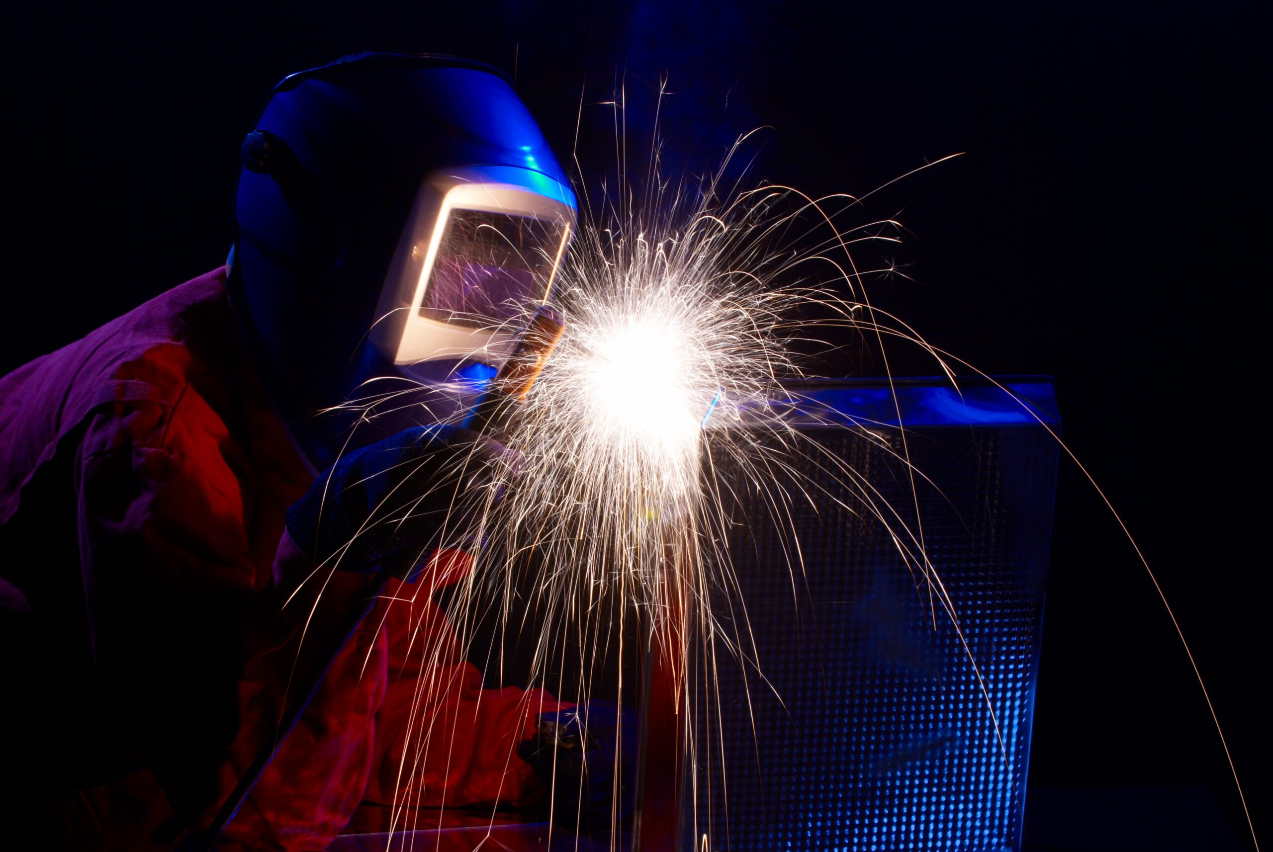 Soldador treballant al taller de reparació i manteniment de maquinària industrial.